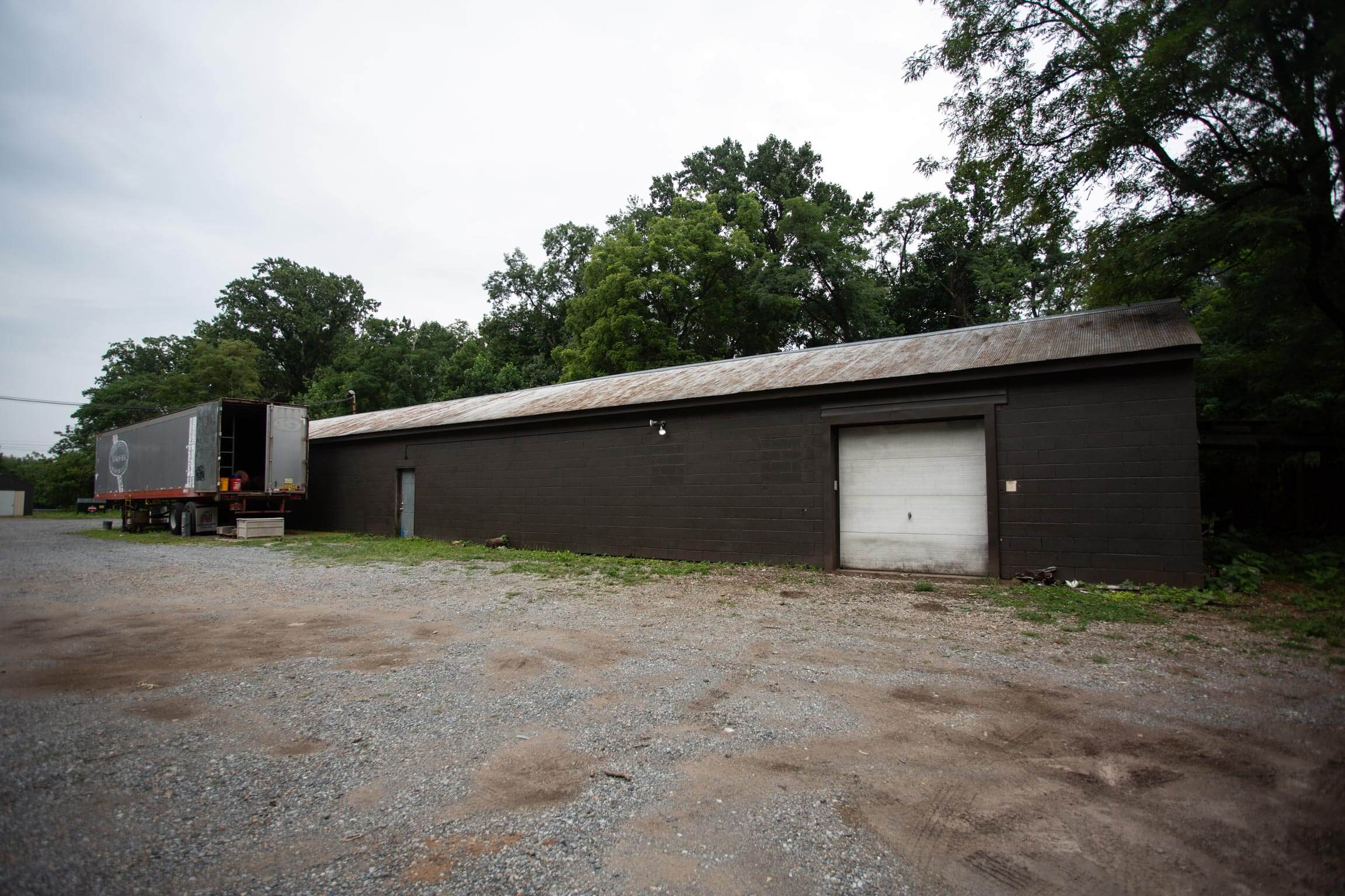 Front view of a single-story garage building and gravel lot, recently purchased by We Buy Garages in Central PA.